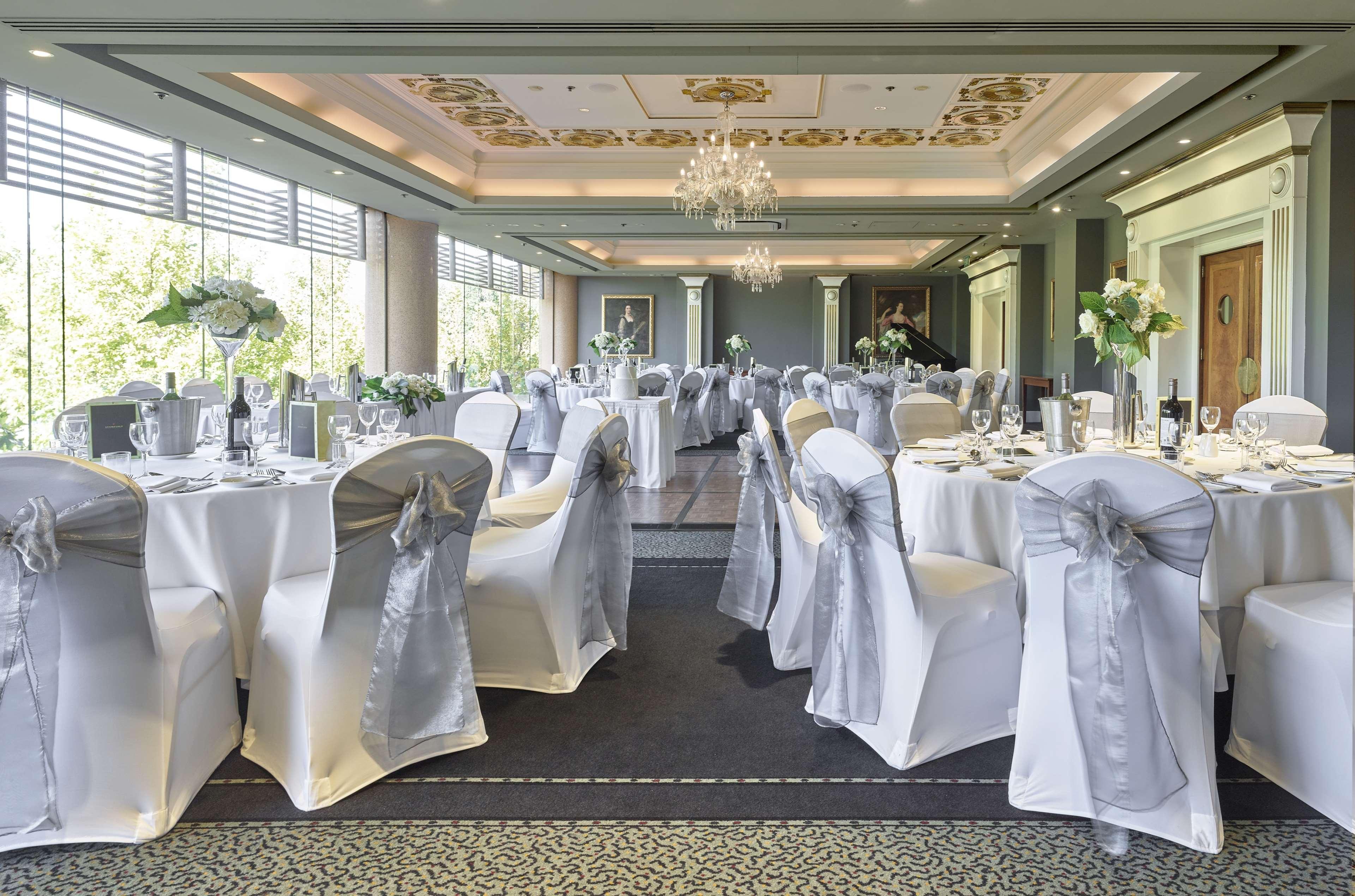 Stamford Plaza Adelaide Hotel Kültér fotó The photo displays an elegantly arranged banquet hall. The room features several round tables covered with white tablecloths, each adorned with silver sashes on the chairs. There are floral centerpieces, possibly white flowers, on the tables, adding 